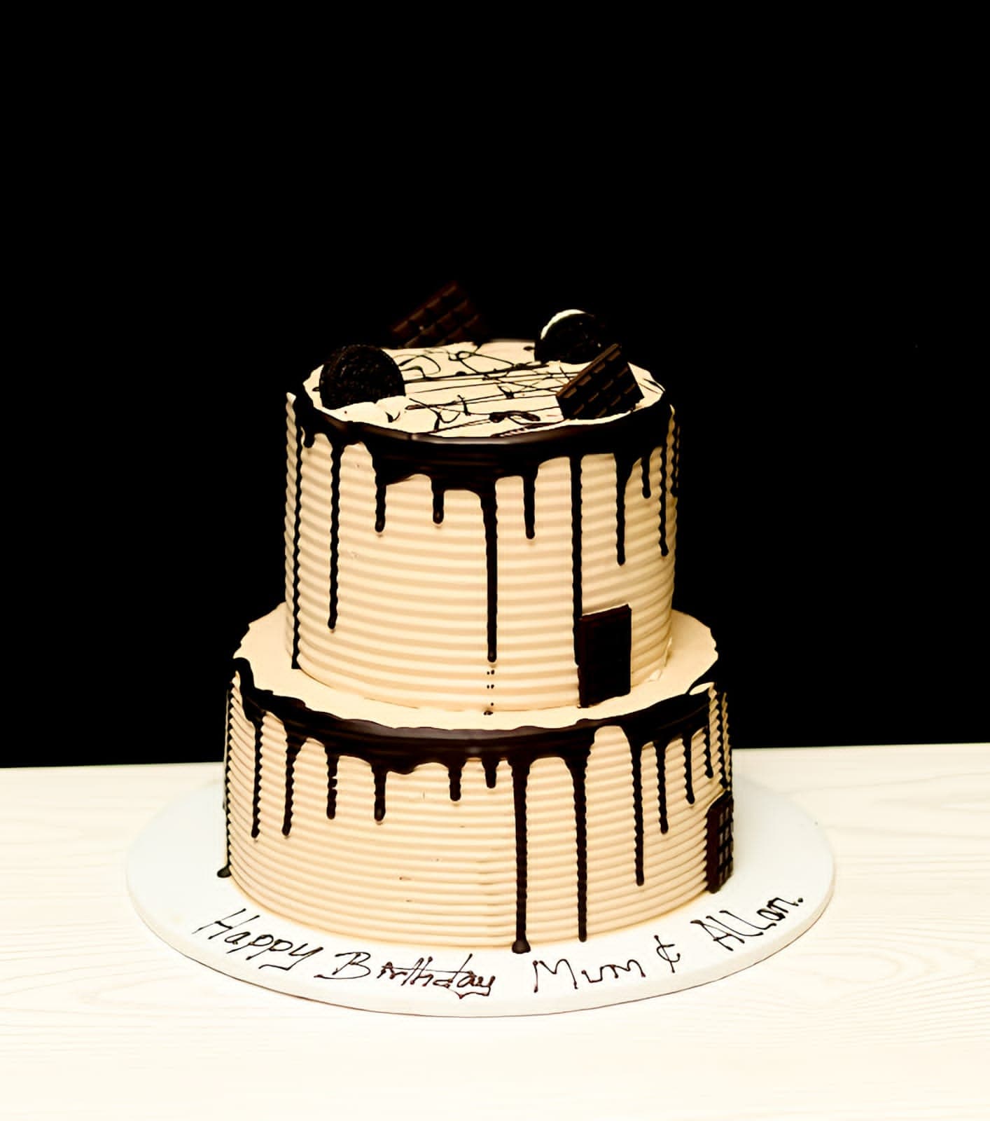 Two-tier cream cake with heavy dark chocolate drip on both tiers