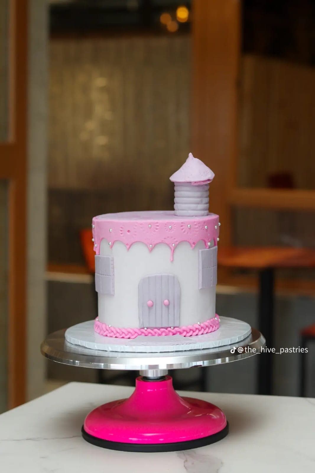 Pink and white fondant castle cake with a turret and braided base
