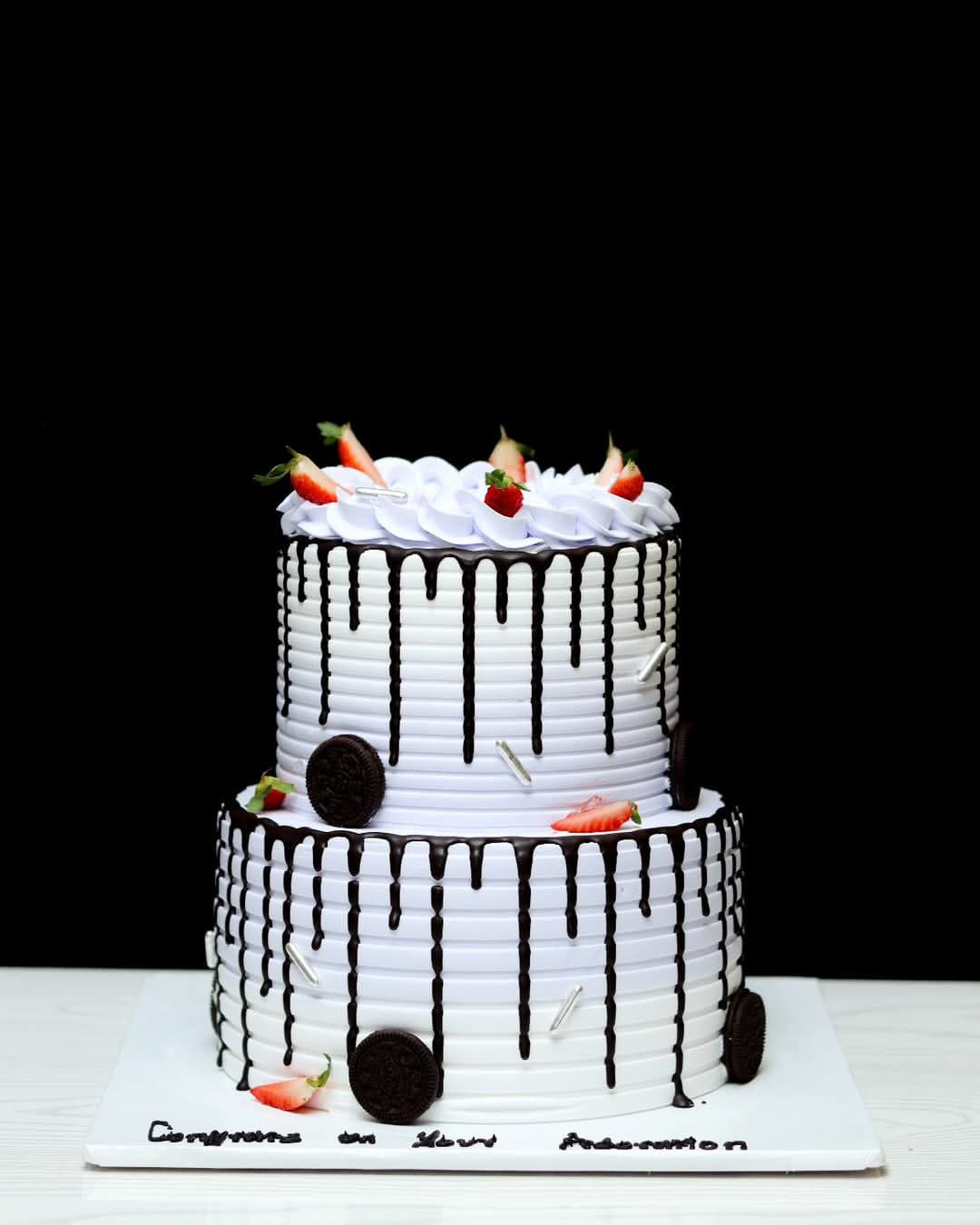 Two-tier white cake with dark chocolate drip and fresh strawberries for a graduation