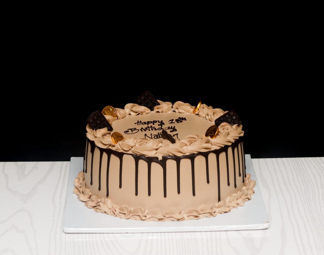 Mocha buttercream cake with dark chocolate drip, chocolate bars and gold coins